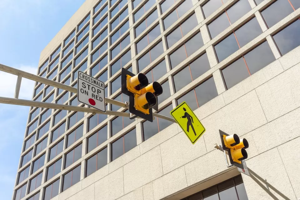 Low angle view of a pedestrian crosswalk traffic signal lights in a city.